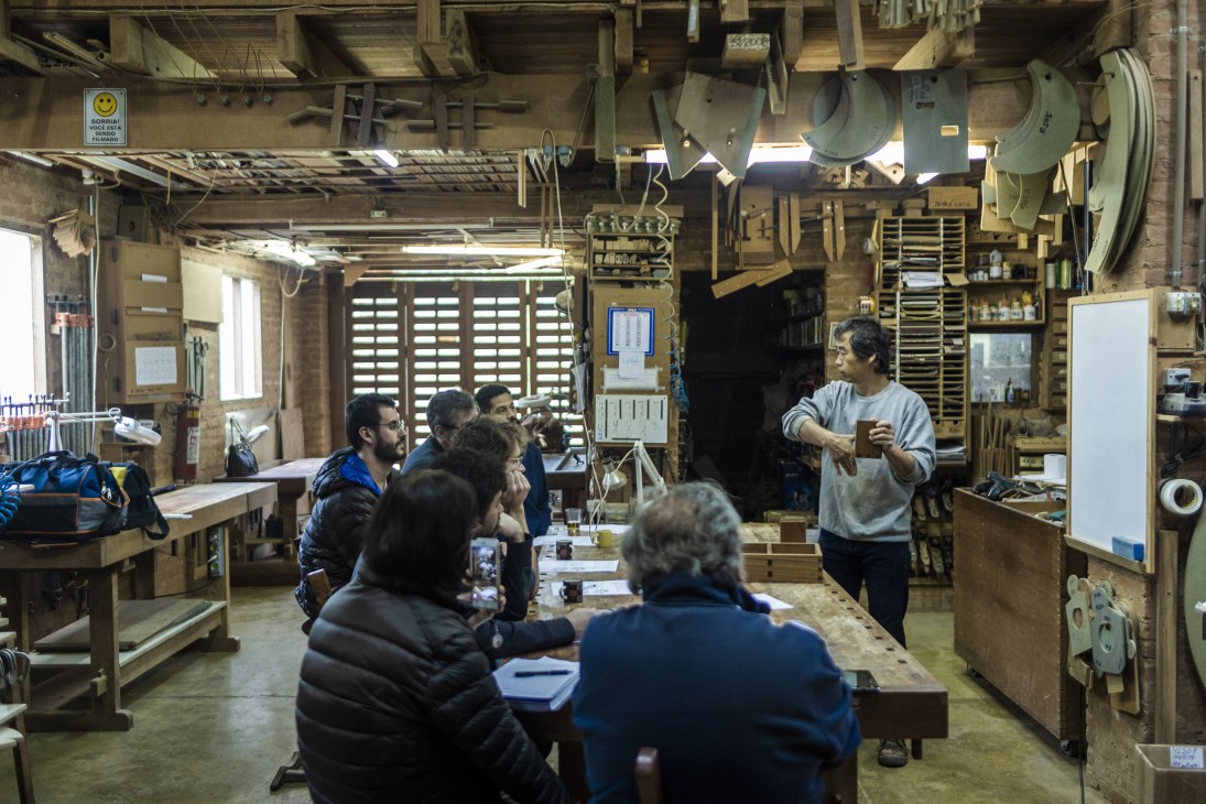 Morito Ebine demonstrates woodworking techniques to visitors inside his carpentry atelier studio.