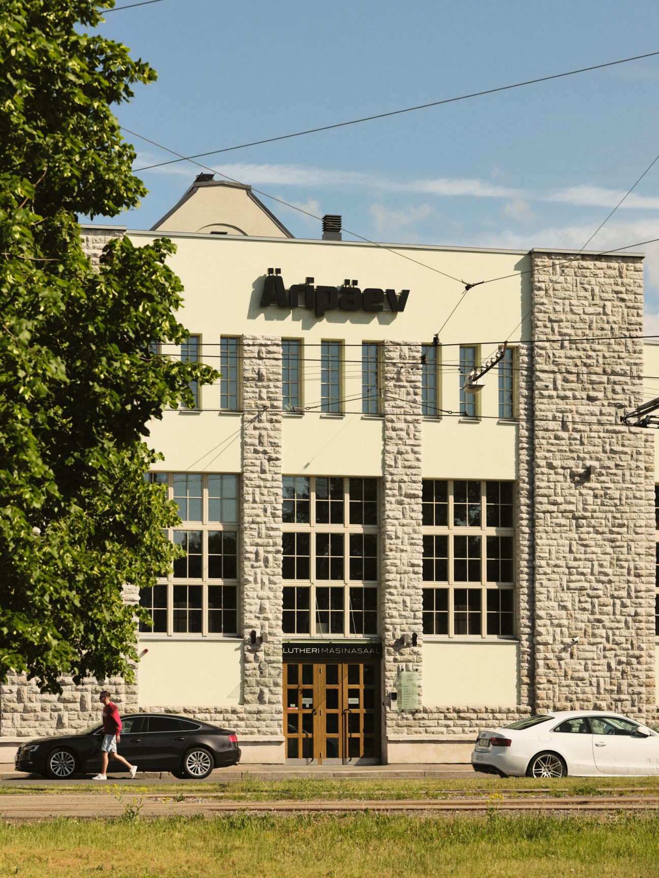 Exterior of a modernist stone and cream-colored building with large windows and signage