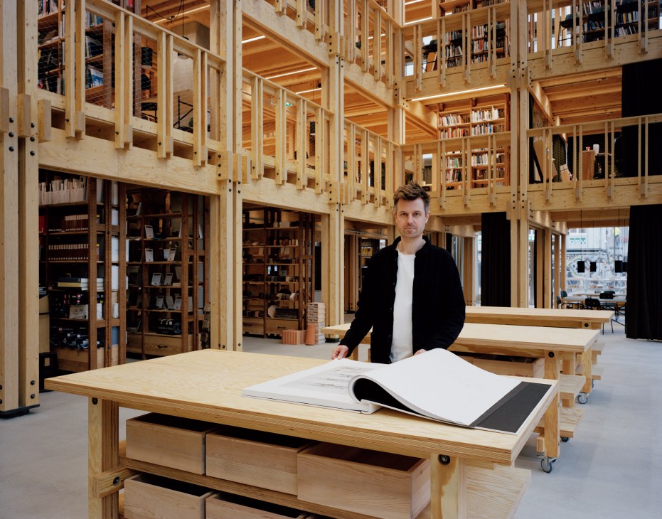 Martin Krogh standing in the timber library with tall wooden shelving and natural lighting