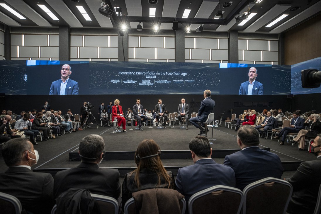 Panel discussion at diplomatic forum with moderator and speakers seated on stage before audience