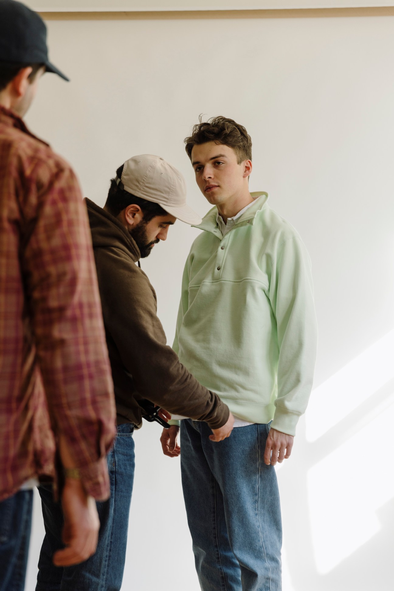 Three men in casual menswear during what appears to be a fitting or styling session