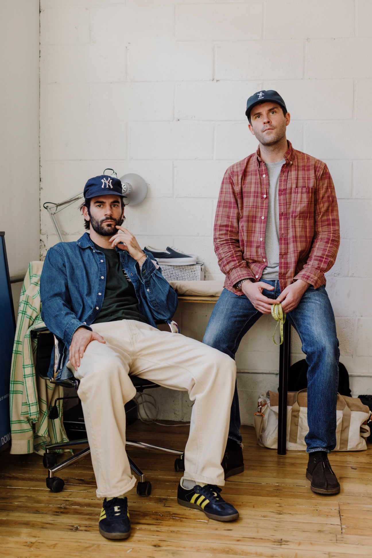 Two men in casual menswear posing in workspace setting