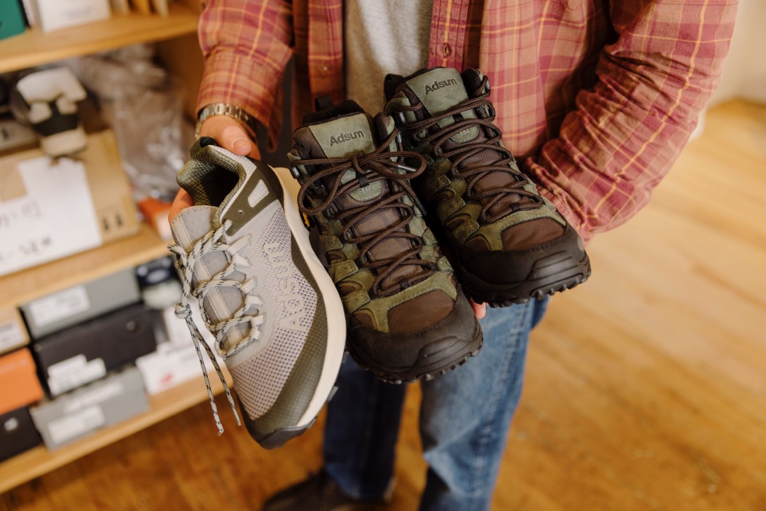 Person holding hiking boots comparing different outdoor footwear styles
