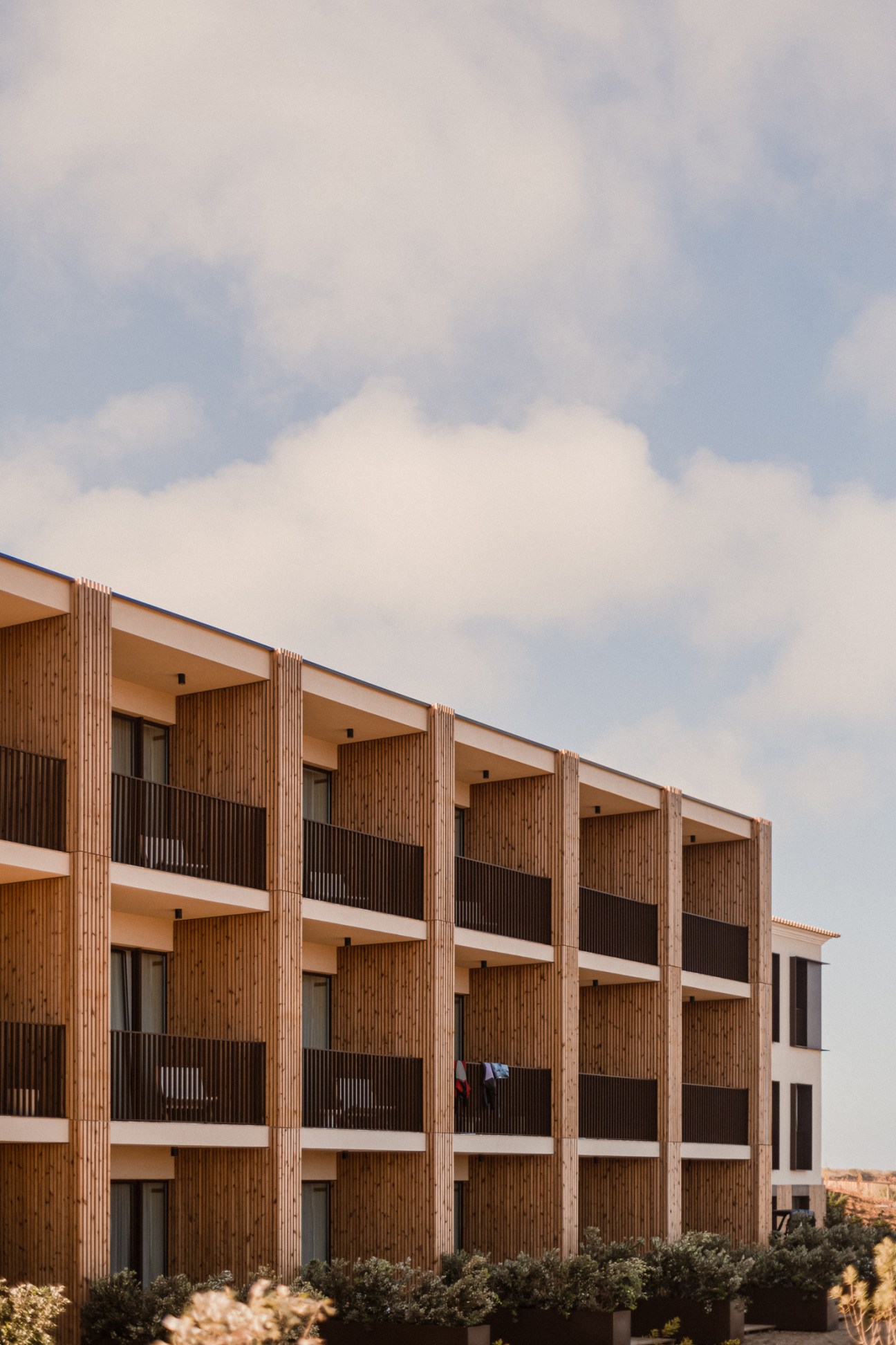 Modern hotel building with wooden facade and balconies set against cloudy sky