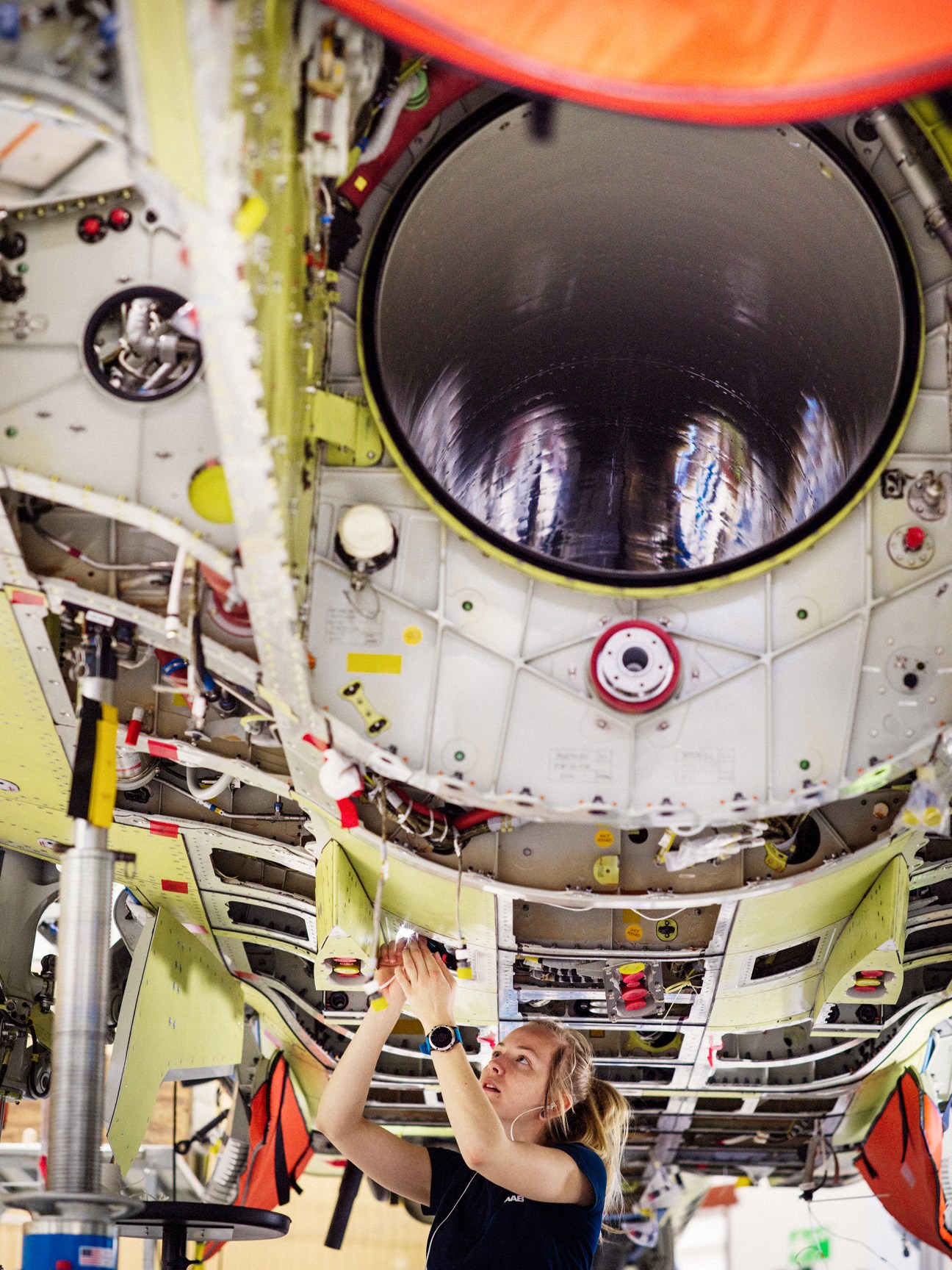 Saab assembly line worker in protective gear working on fighter jet components in the Linköping manufacturing facility