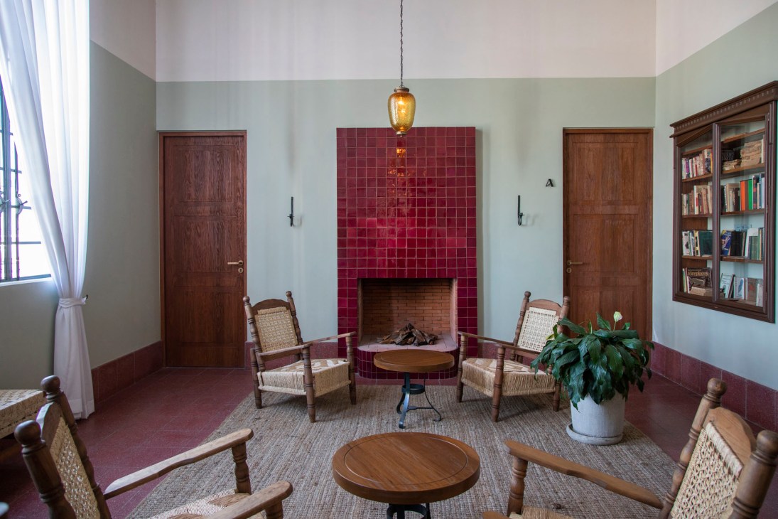 Interior room at Baja Club with burgundy tile fireplace, wooden doors, woven chairs, and bookshelves.
