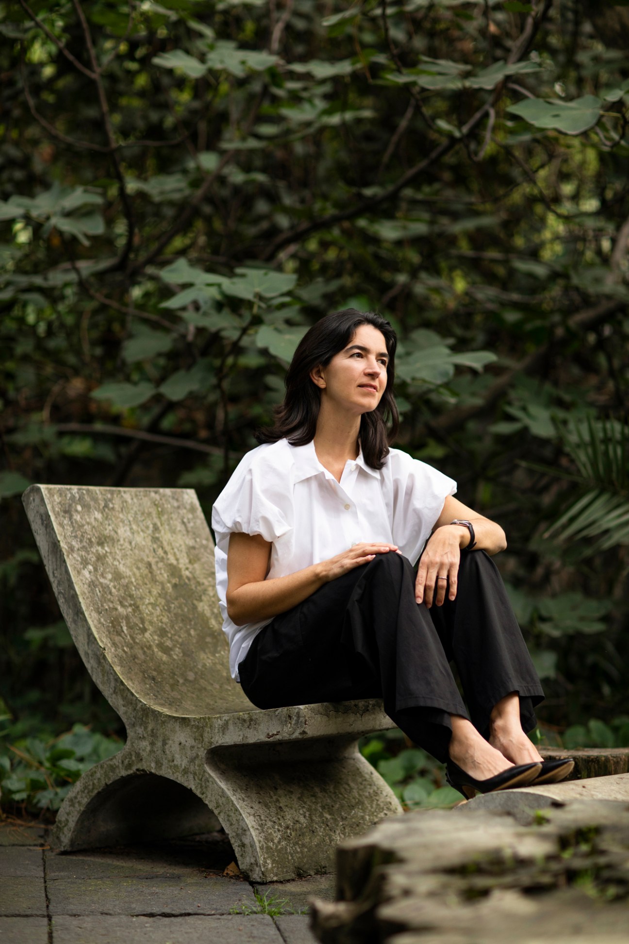 Fernanda Canales sitting in a concrete outdoor chair inspired by traditional Mexican design in her garden