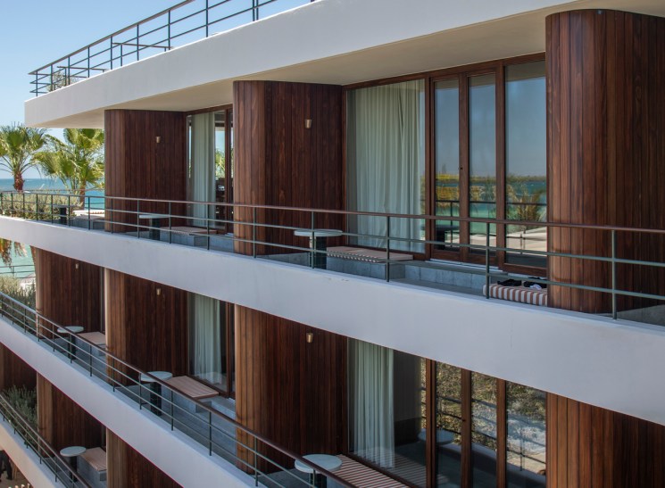 Ocean-view balconies at Baja Club with wood-panelled walls and striped seating overlooking the coastal landscape.