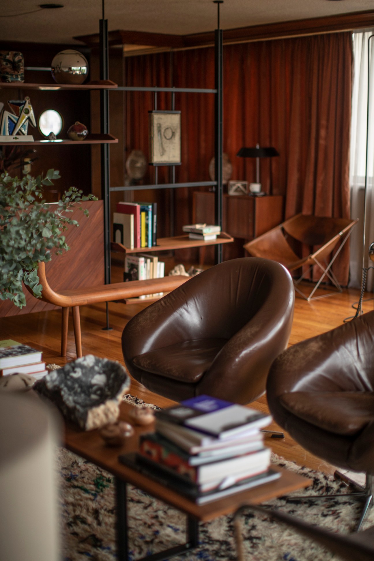 Floor-to-ceiling shelving unit with books, decorative objects, and artwork in a modernist interior