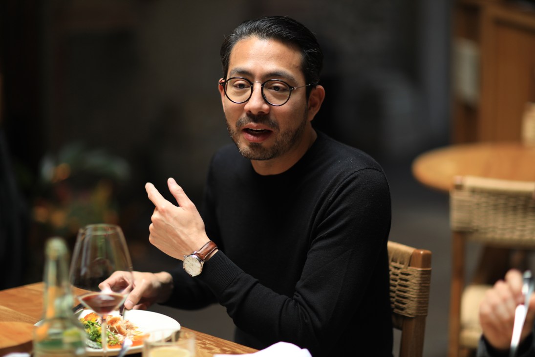Edo Kobayashi gestures while speaking at a dining table during a roundtable discussion.