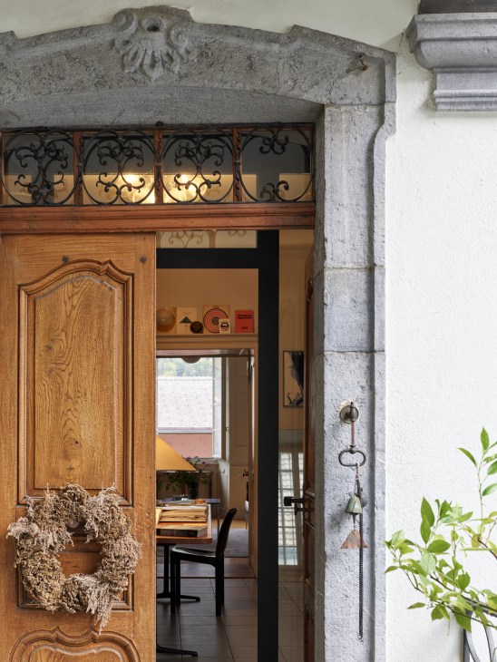 Entrance to a Swiss apartment showing wooden architectural details and terrace access from an inner courtyard