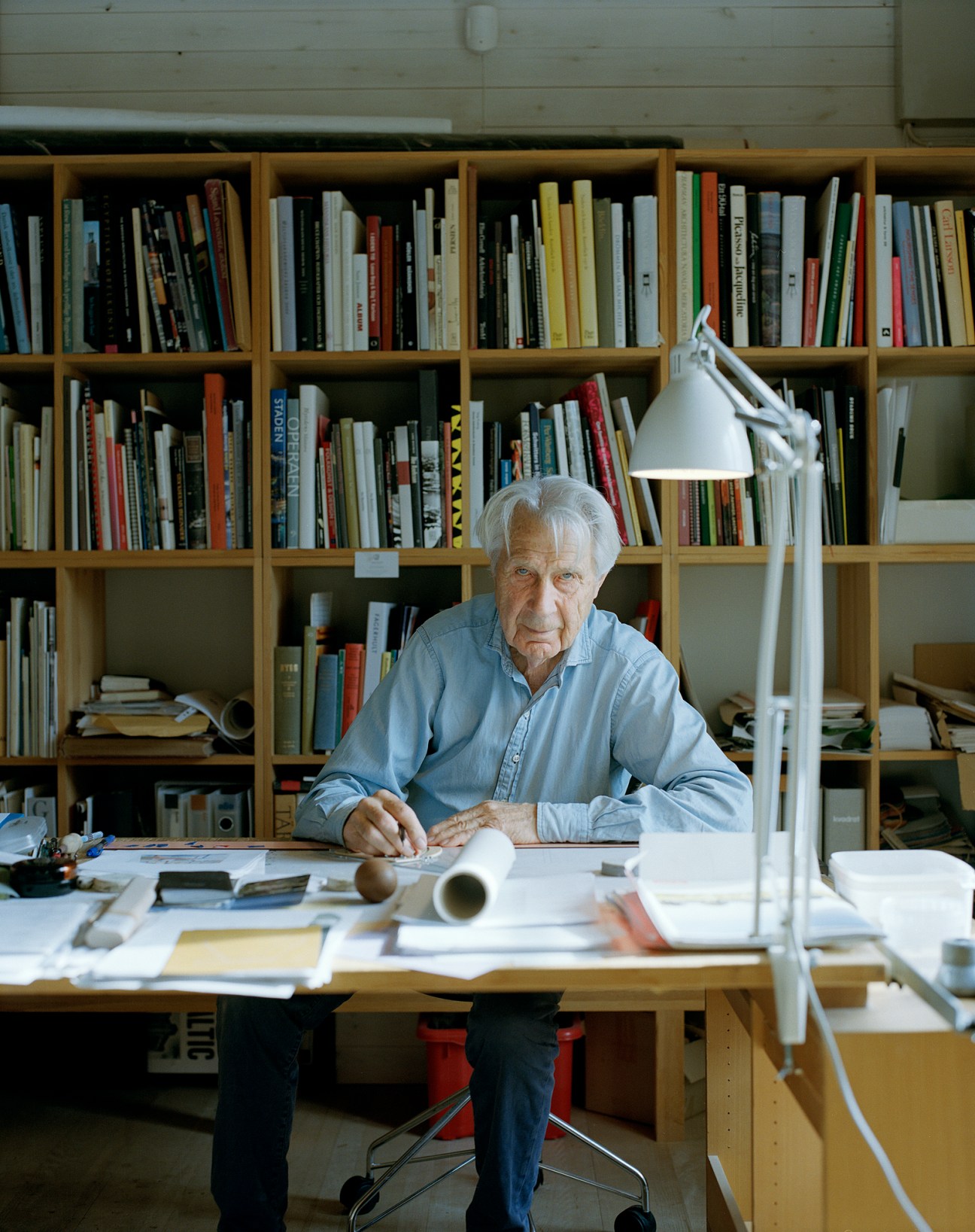 Åke Axelsson, 88-year-old Swedish interior architect, sitting at his desk in his studio surrounded by books and papers