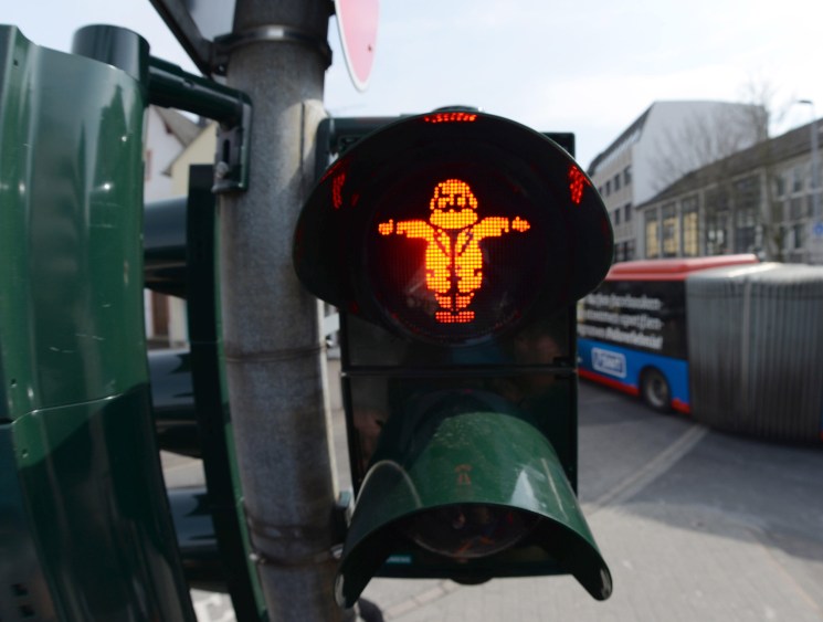 Red pedestrian traffic light showing a figure with arms outstretched in Karl Marx commemoration in Trier, Germany.