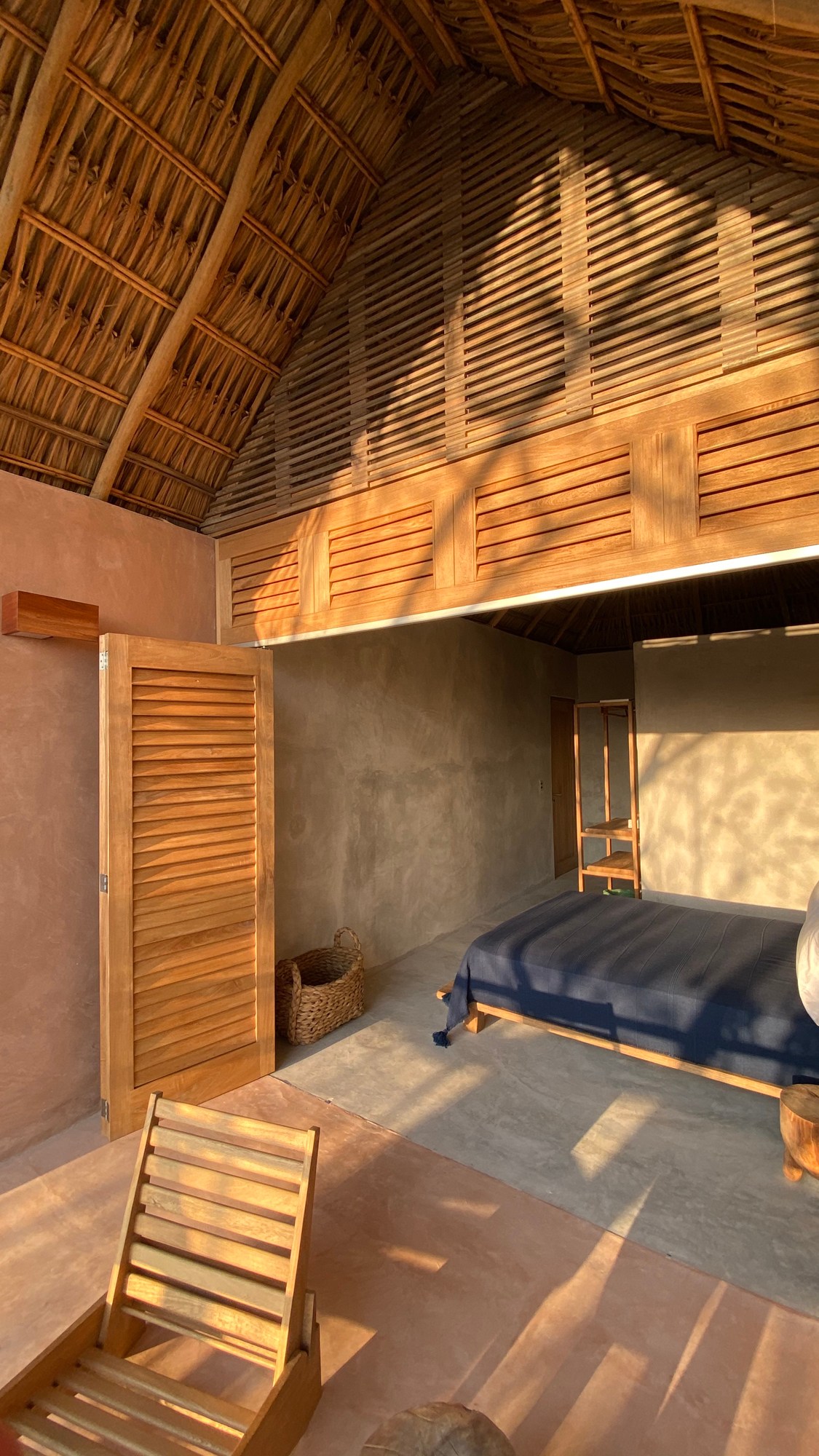 Interior bedroom at Monte Uzulu hotel showing natural materials, exposed wooden ceiling beams and minimalist design