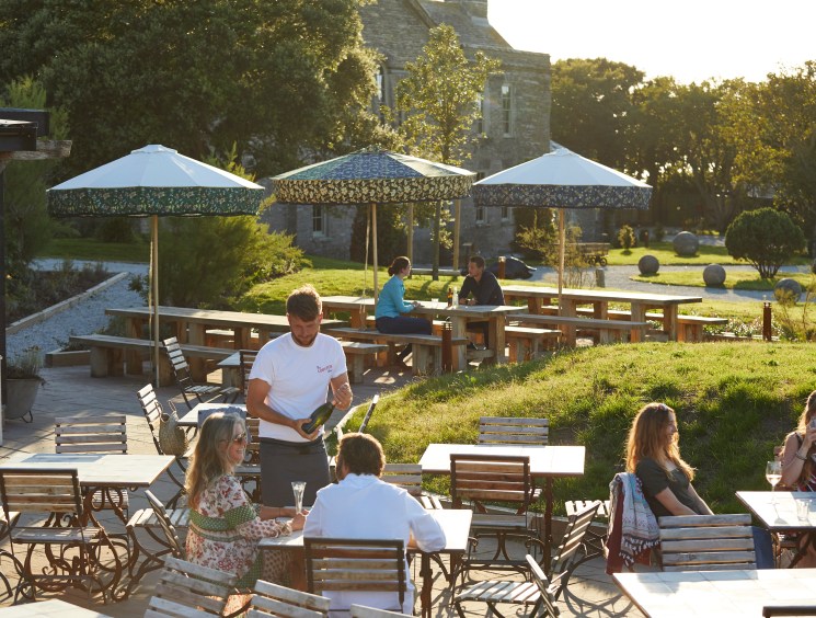 Outdoor dining area with wooden tables and umbrellas at The Pig at Harlyn Bay hotel