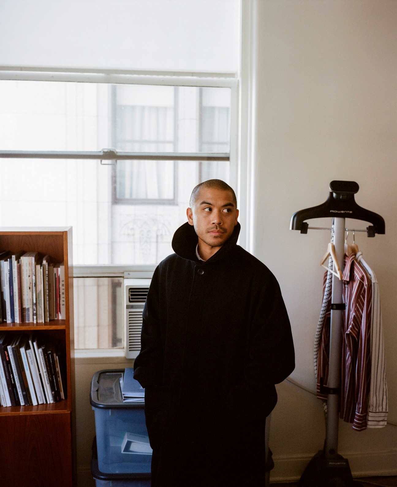 Reuben Perin, brand director at And Austin, wearing black hoodie in workspace with bookshelf and clothing rack