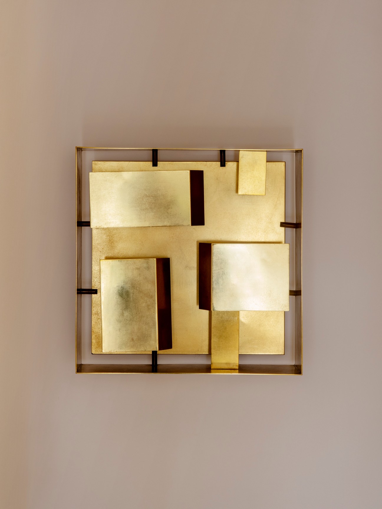 Modern geometric wall sconce with angular brass and glass panels in a square frame