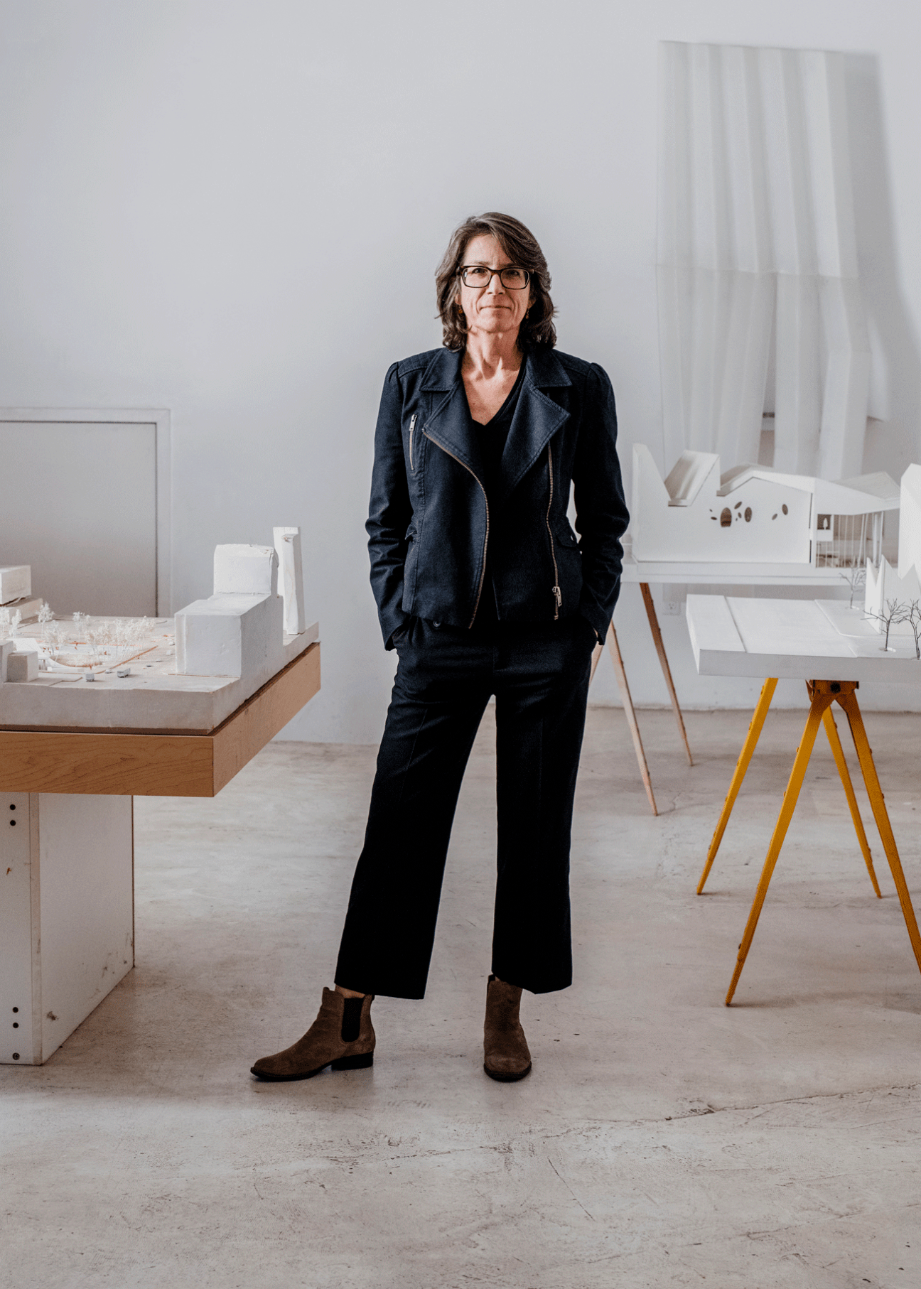 Angela Brooks standing in an architecture studio with white building models on tables