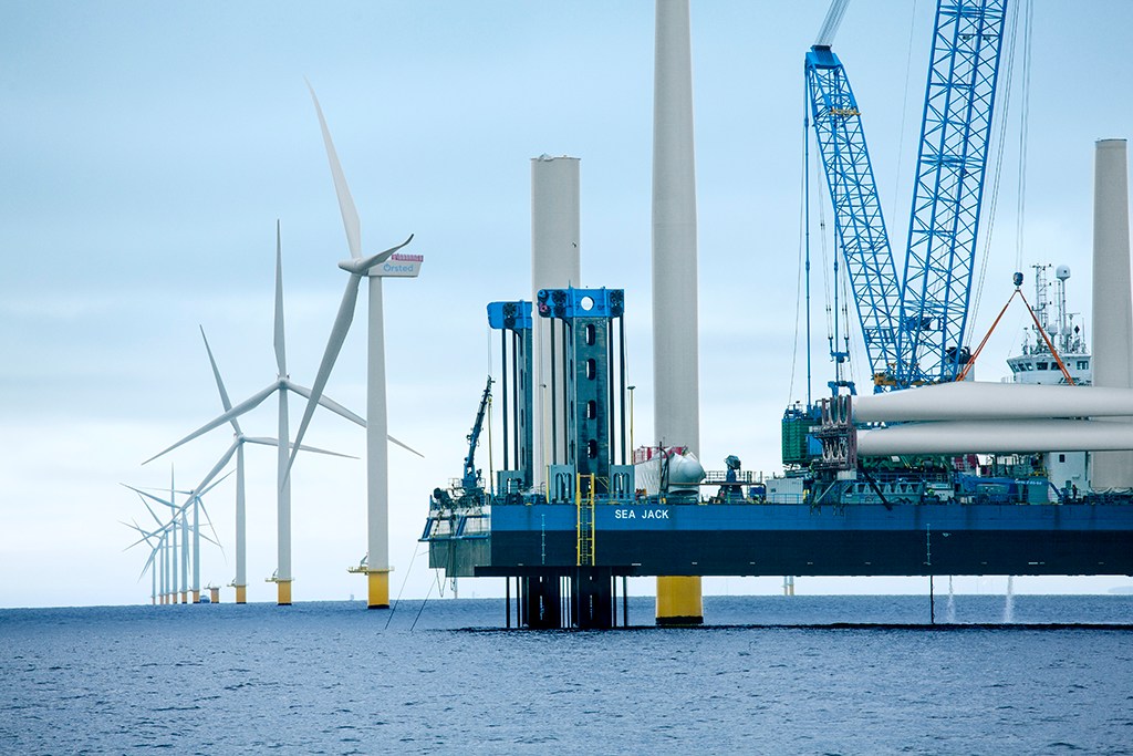 Large offshore wind turbines being constructed at sea with installation vessel and crane equipment visible