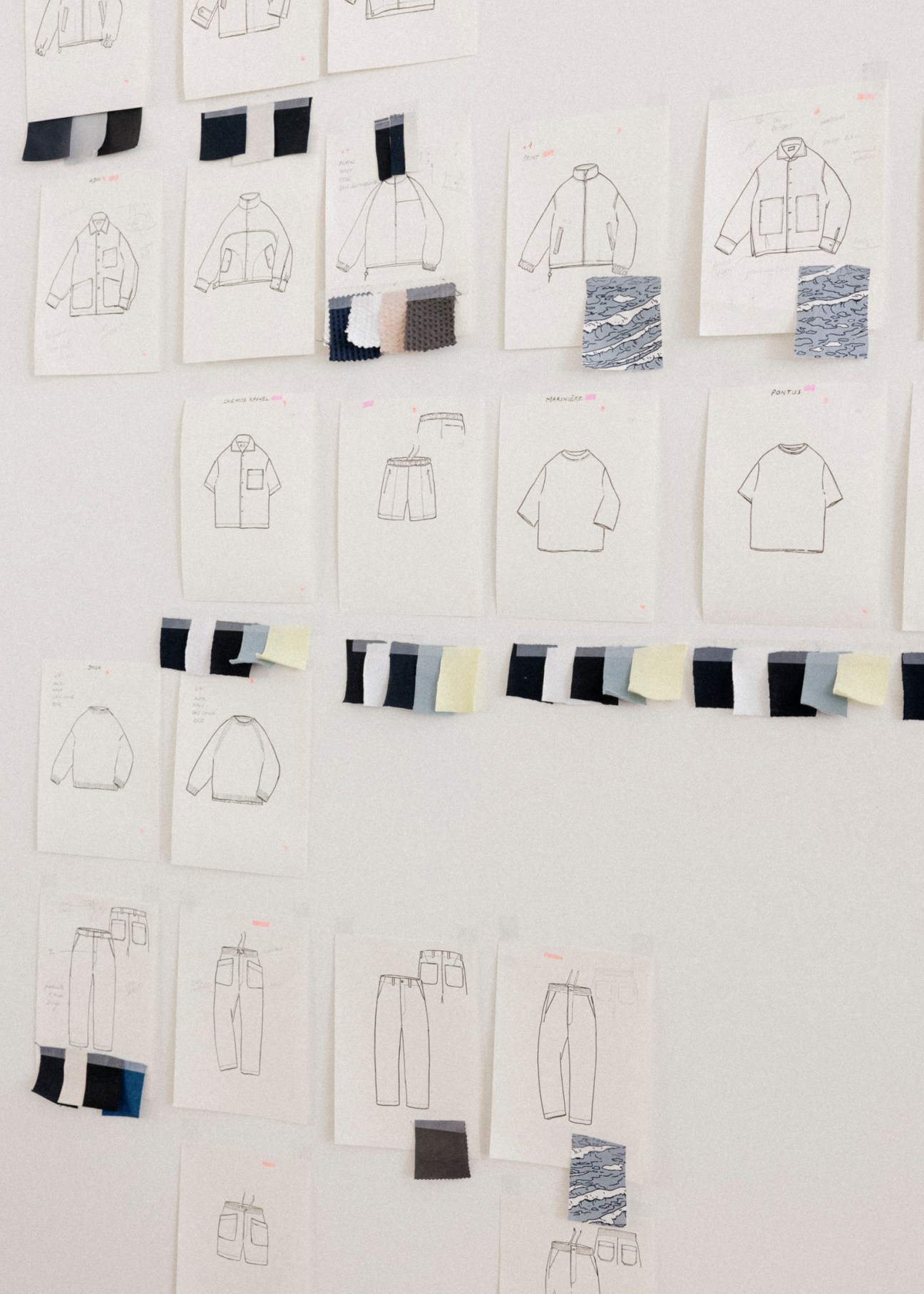 Fashion design sketches and fabric swatches arranged on white paper showing clothing technical drawings