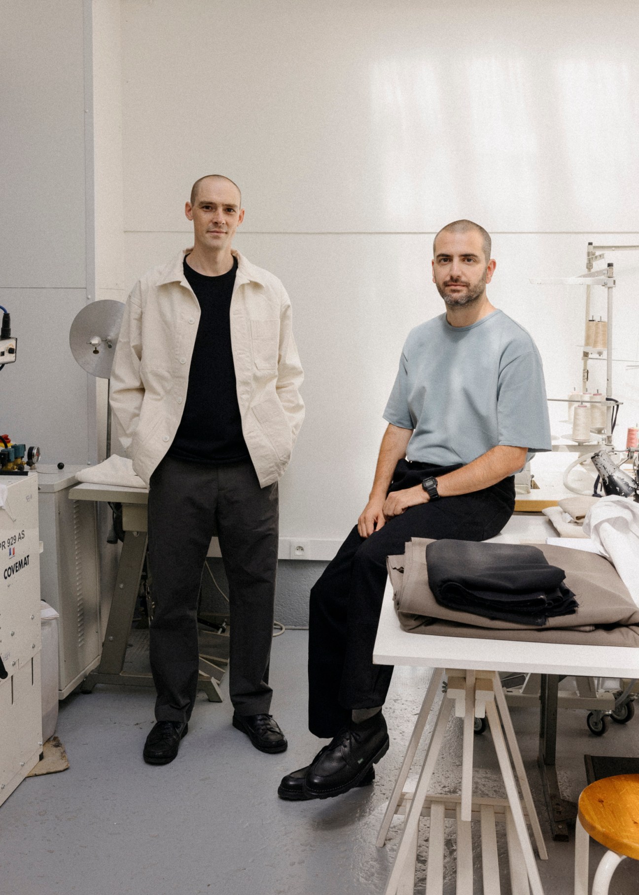 Laurent Bourven and Marc Asseily of Arpenteur standing in their workshop with fabric samples and clothing
