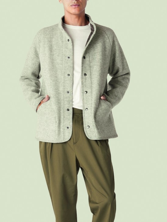 Man wearing Arpenteur × Monocle Contour wool jacket in grey over white t-shirt and olive trousers.