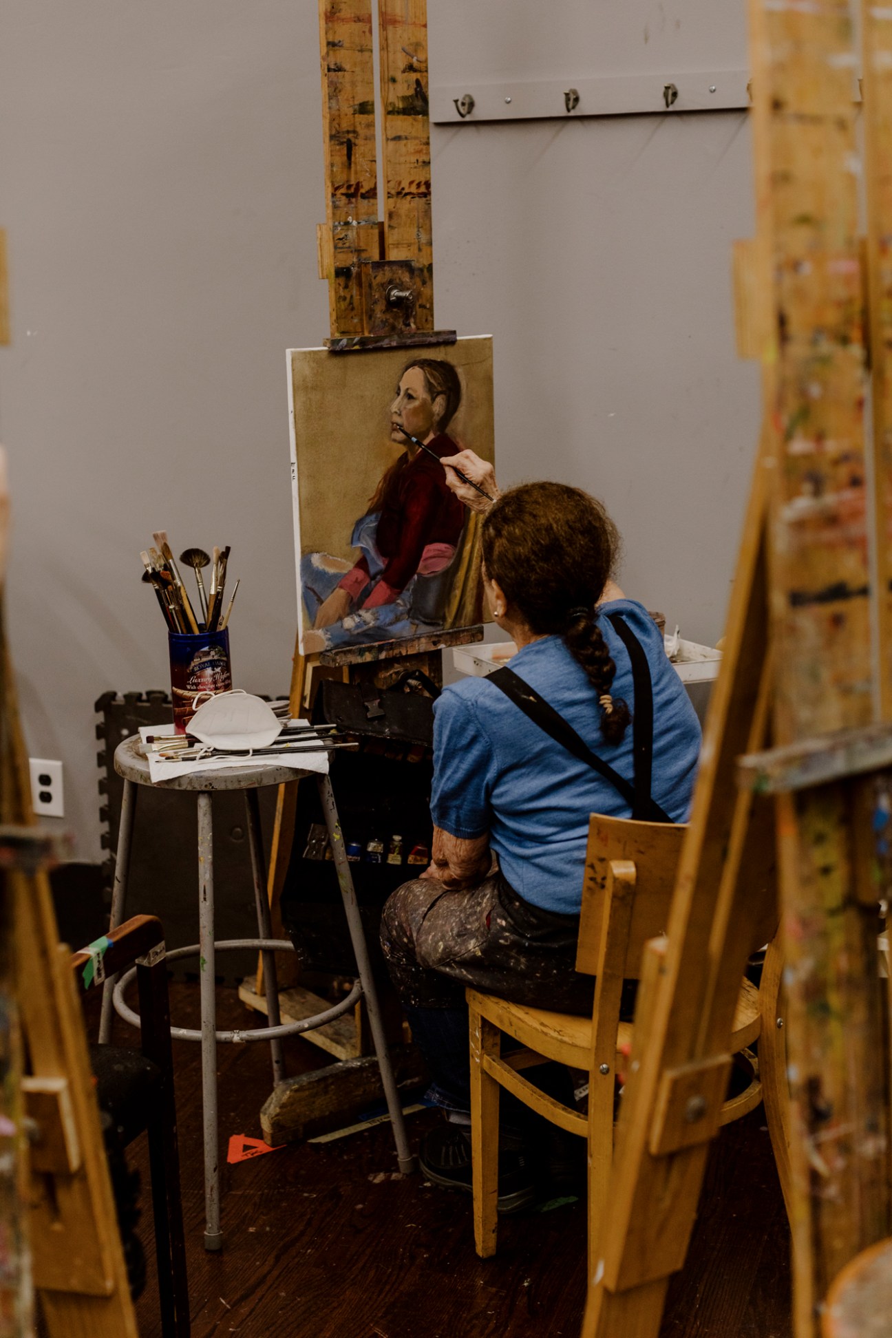Student painting a portrait from a live model in an art studio class.