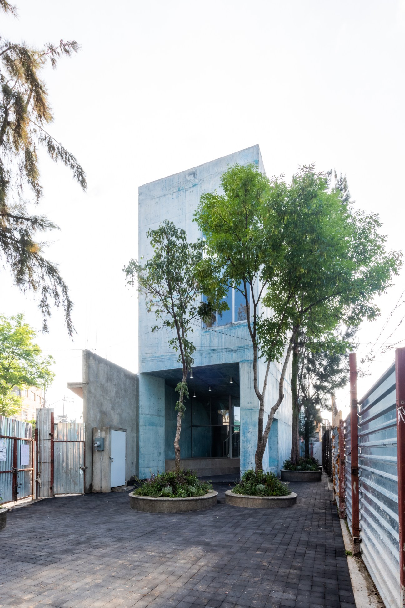 Exterior view of concrete Pilares community center with trees and paved courtyard in Mexico City