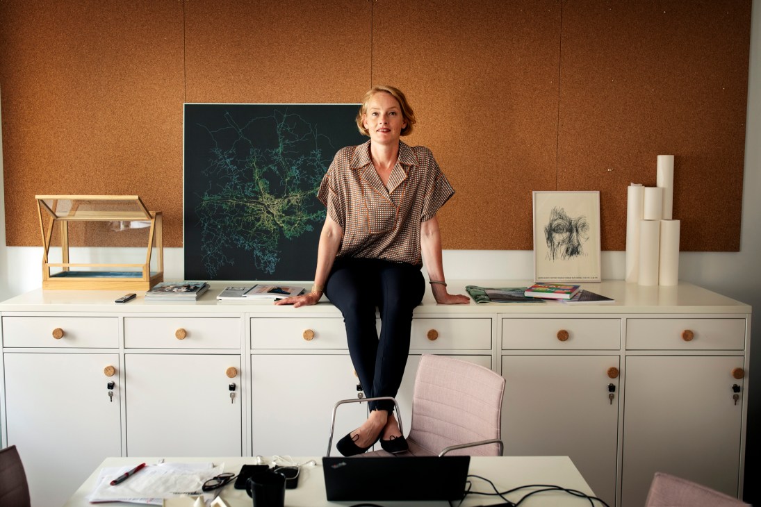 Alexandra Hagen, CEO of White Arkitekter, stands in her refurbished conference room workspace with cork walls and shared desk space.