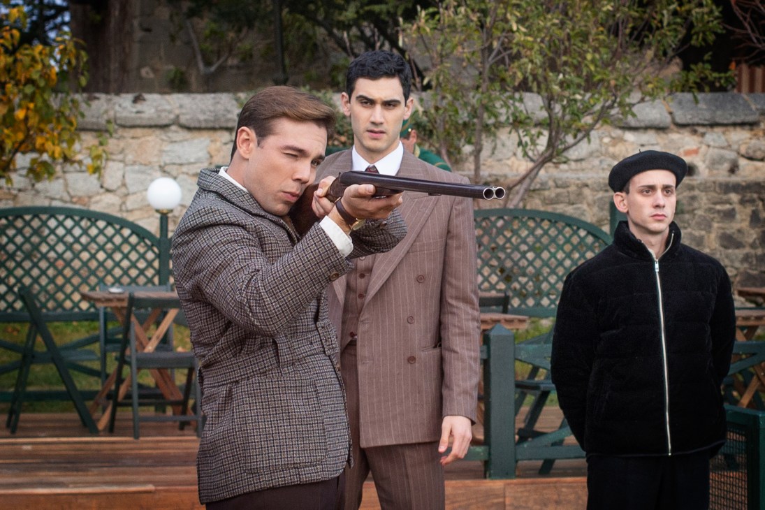 Three men in period costume, one aiming a shotgun while others watch in Netflix's Someone Has to Die