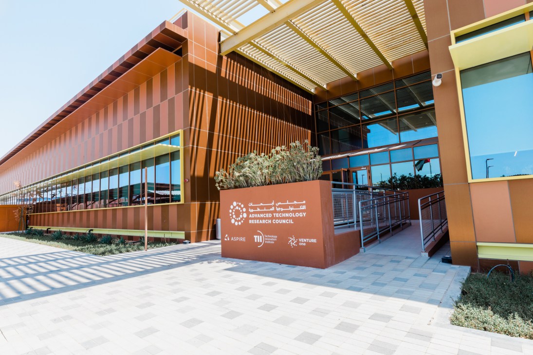 Modern terracotta-colored building with horizontal louvers and large windows housing the Advanced Technology Research Council in Masdar City.