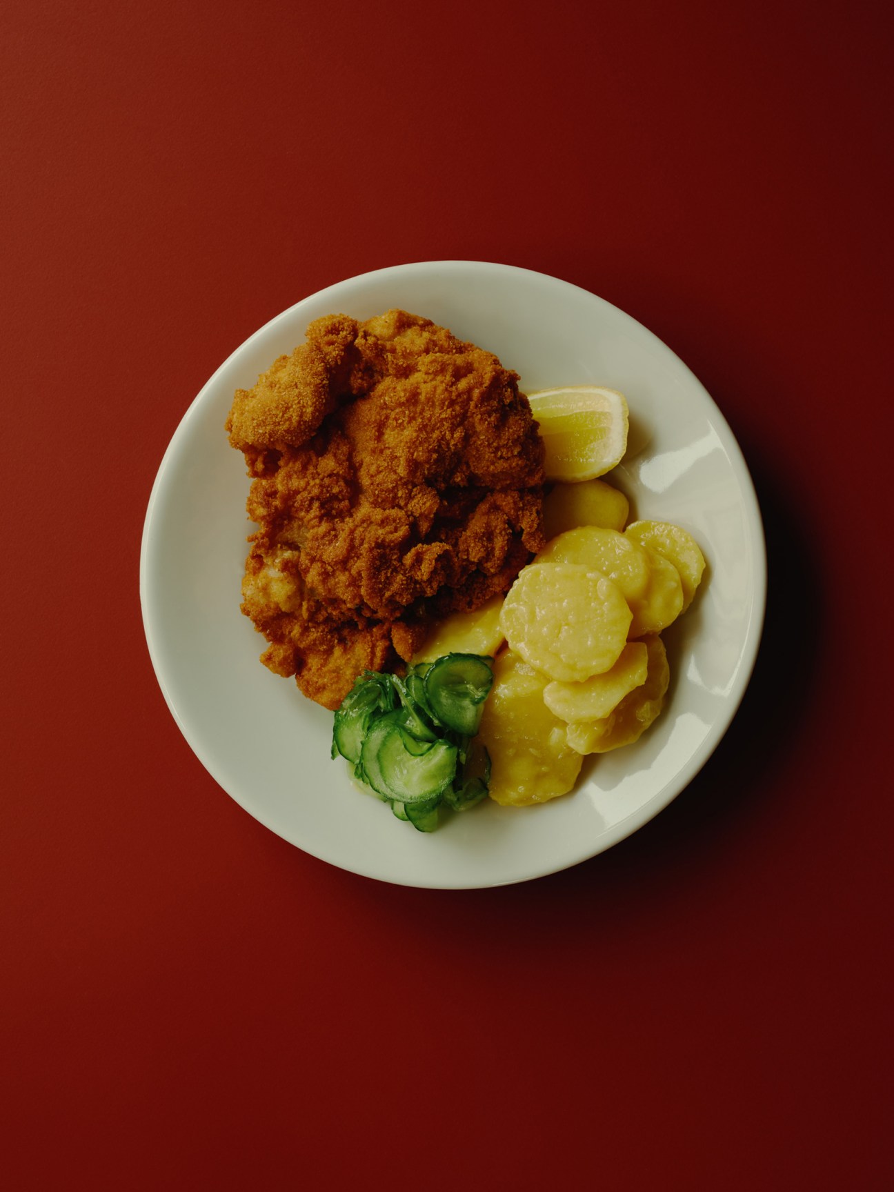 Austrian fried chicken served with pickled vegetables and lime wedge on white plate