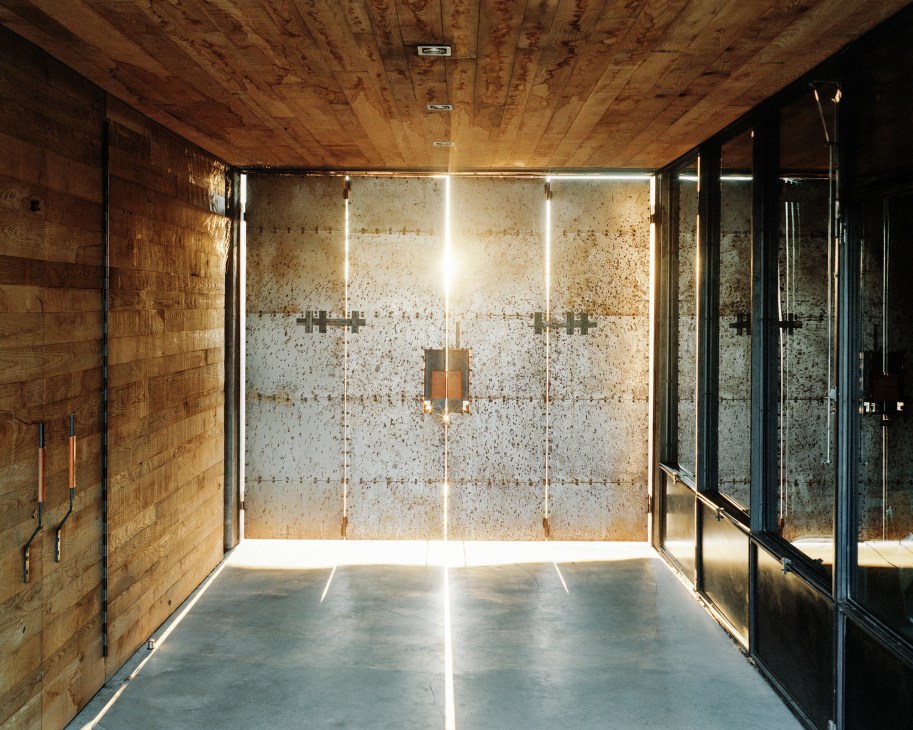 Interior hallway with concrete walls, glass panels, and natural light streaming through at Casa Caldera
