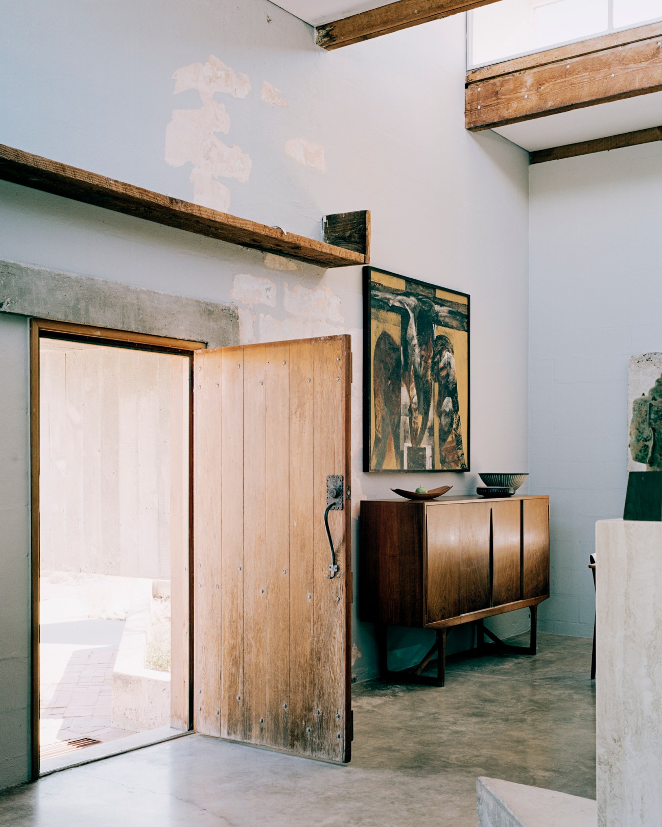 Mid-century modern interior with exposed wooden ceiling beams, sideboard, and framed artwork