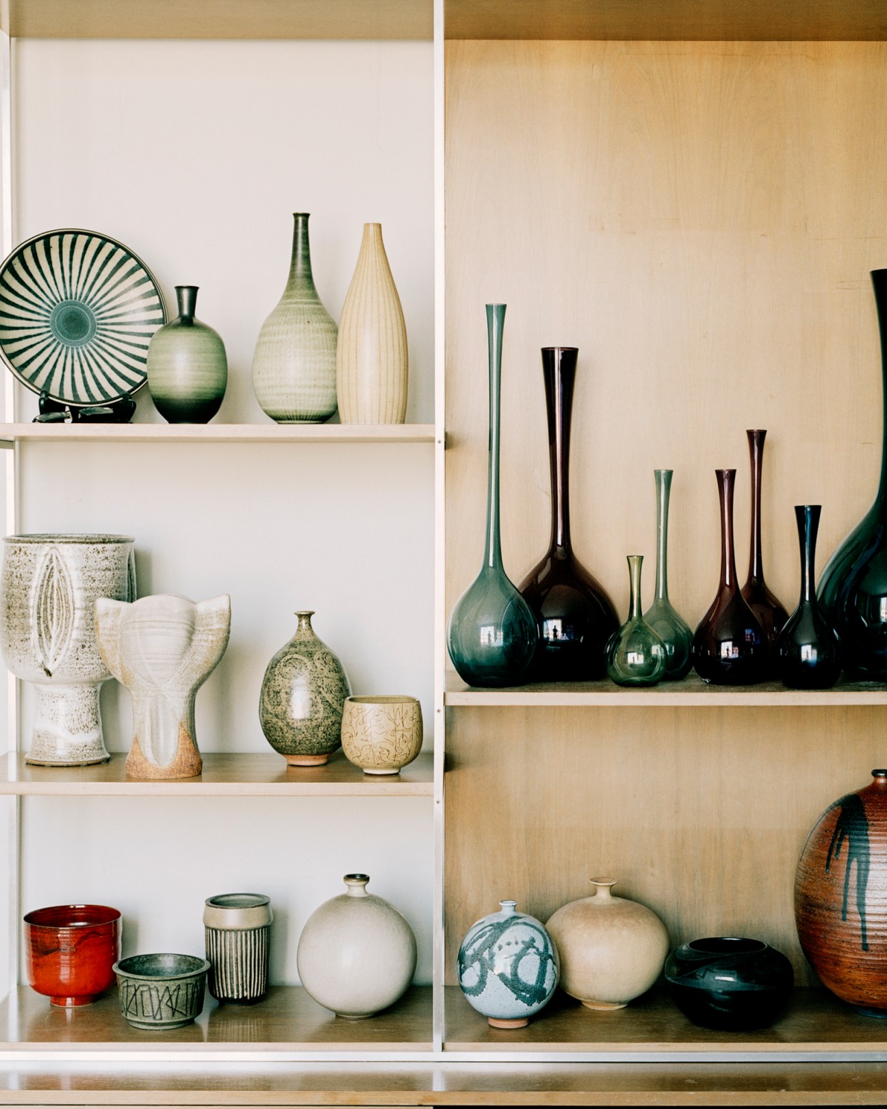 Collection of ceramic vases and pottery displayed on built-in wooden shelving