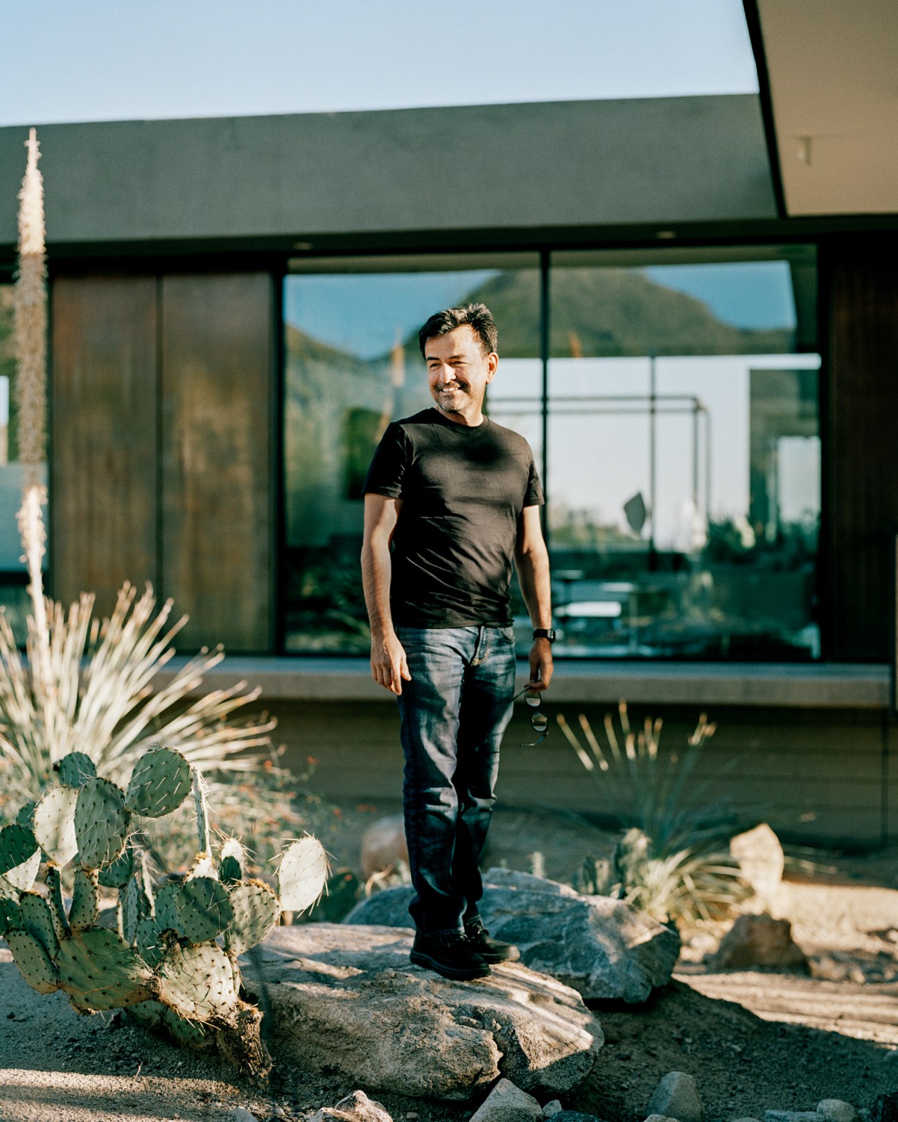 Luis Ibarra standing on concrete walkway with desert landscape and modern house in background