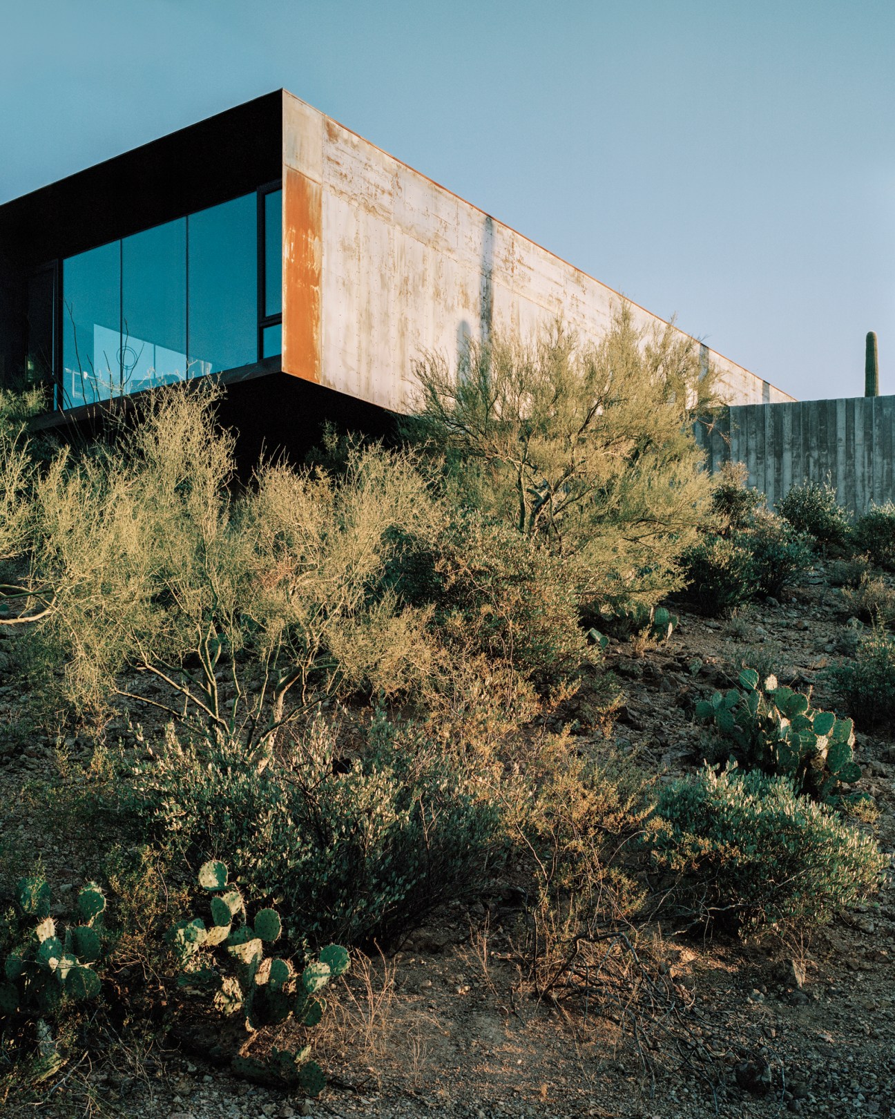 Modern hillside residence with angular concrete forms against desert mountains