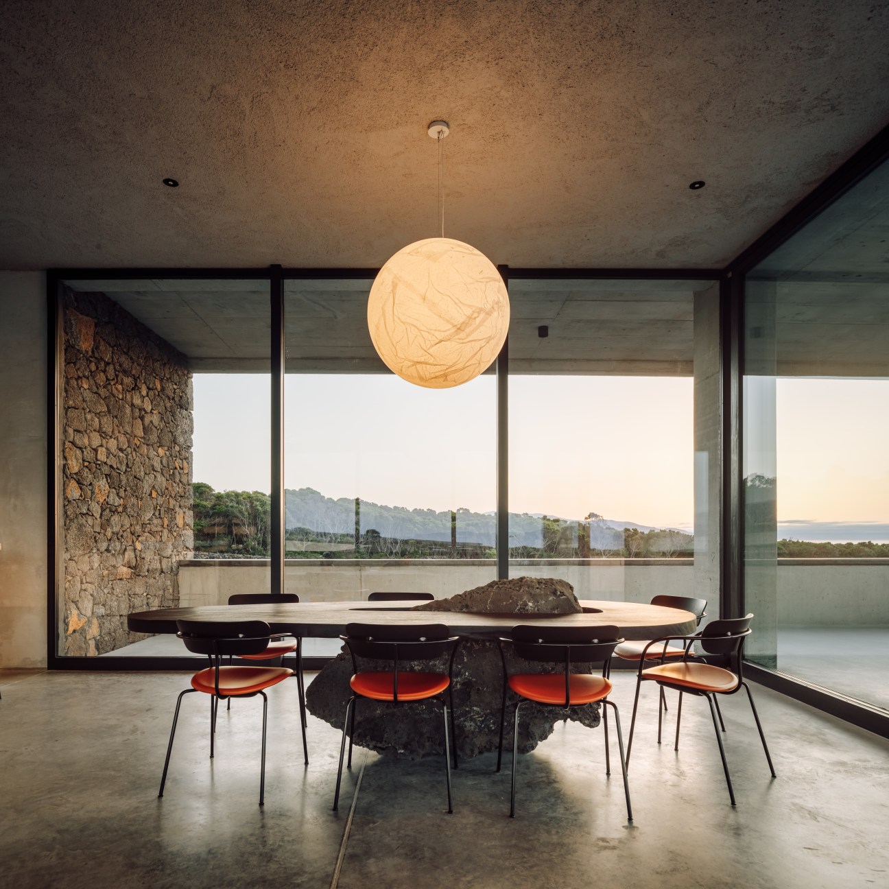 Modern dining room with large spherical pendant light, round table with chairs, and floor-to-ceiling windows