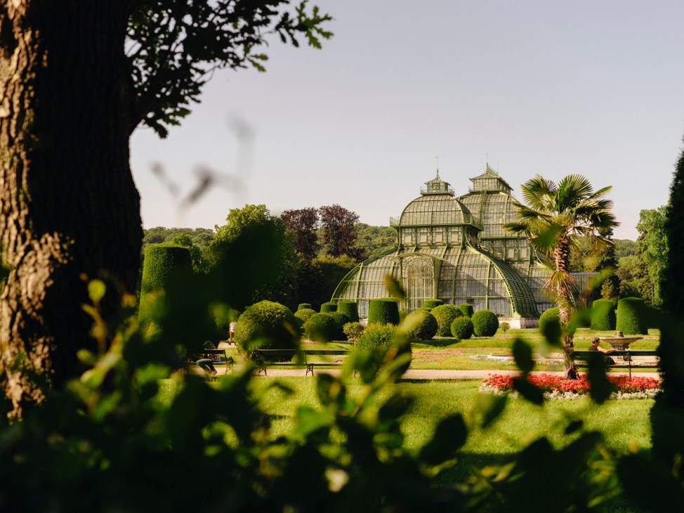 Historic glass greenhouse with ornate dome architecture surrounded by manicured gardens and topiary