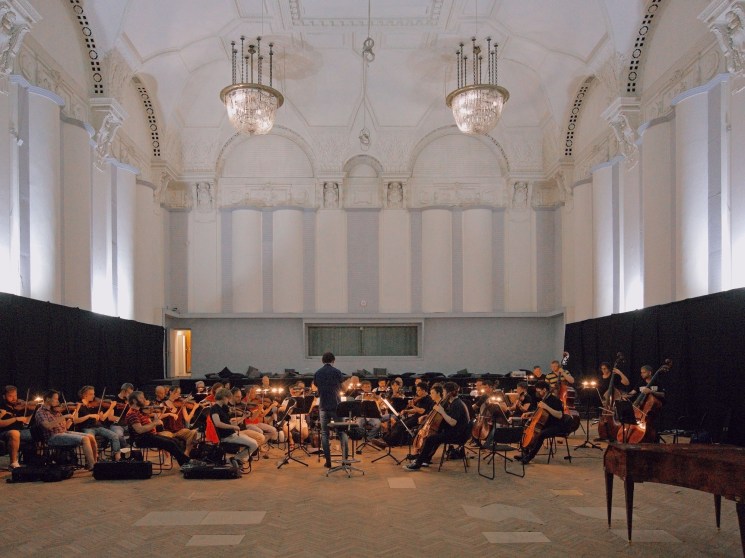 Conductor Teodor Currentzis directing MusicAeterna orchestra during rehearsal in ornate classical concert hall