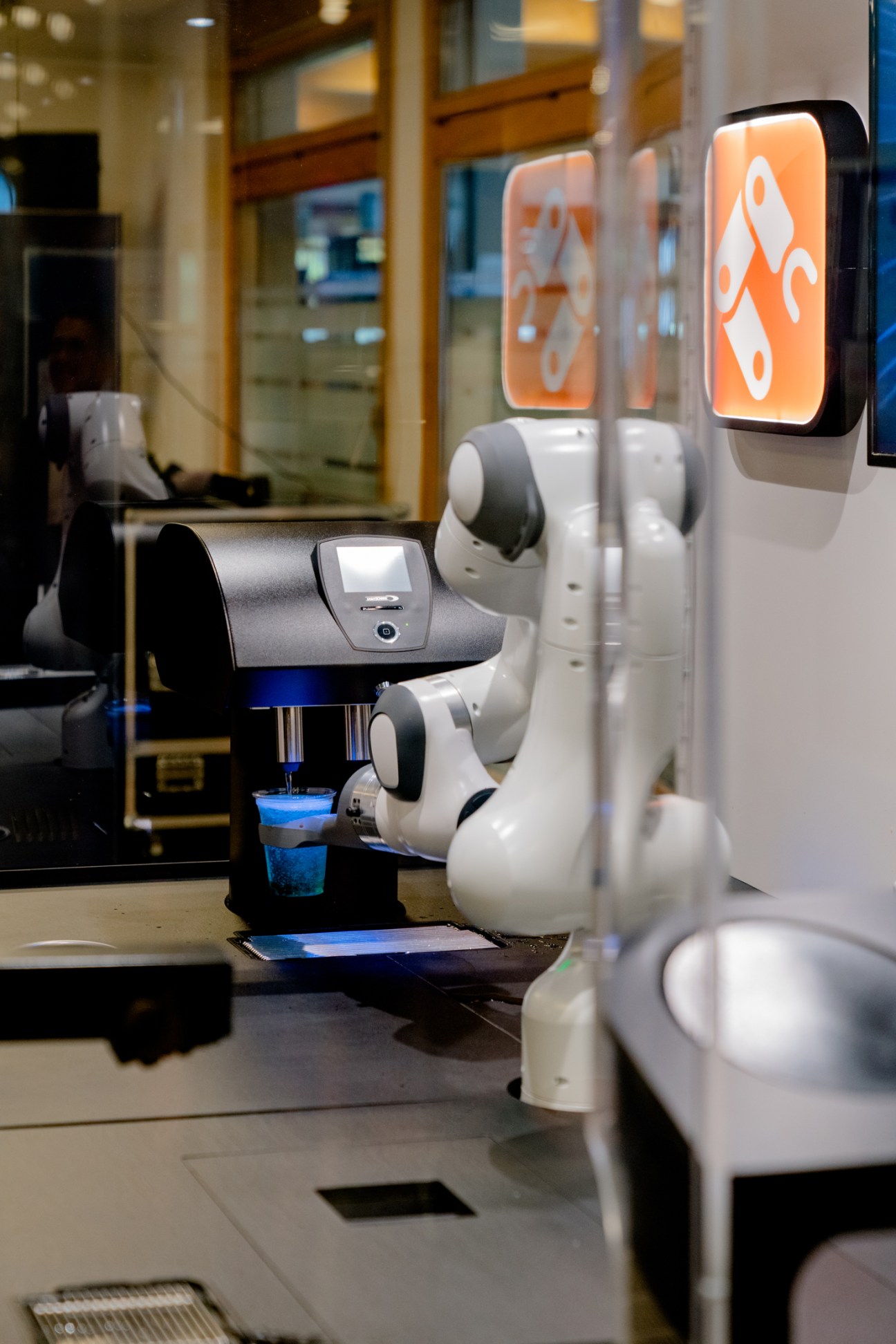 A white robotic coffee serving device on wheels in a modern hospitality training facility