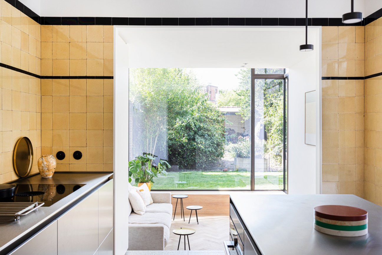 Kitchen interior showing original 1930s yellow tiles paired with contemporary brushed aluminium Bulthaup countertops
