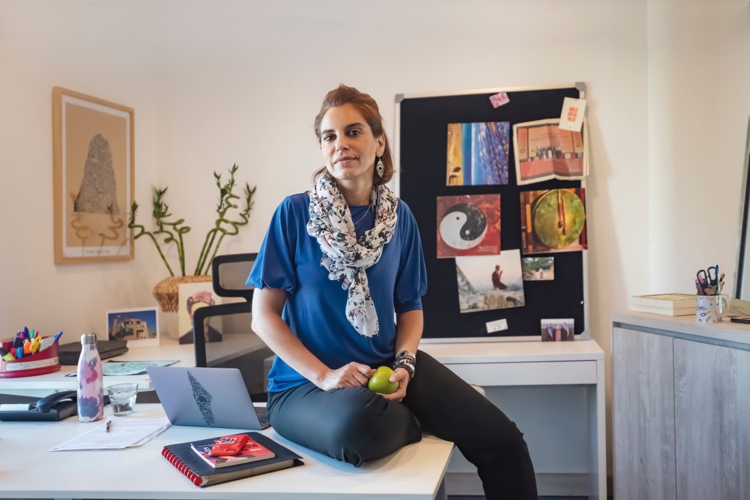 Rama Kayyali, CEO of Little Thinking Minds, sits at her desk in her centrally located glass-walled office with a laptop and personal items.