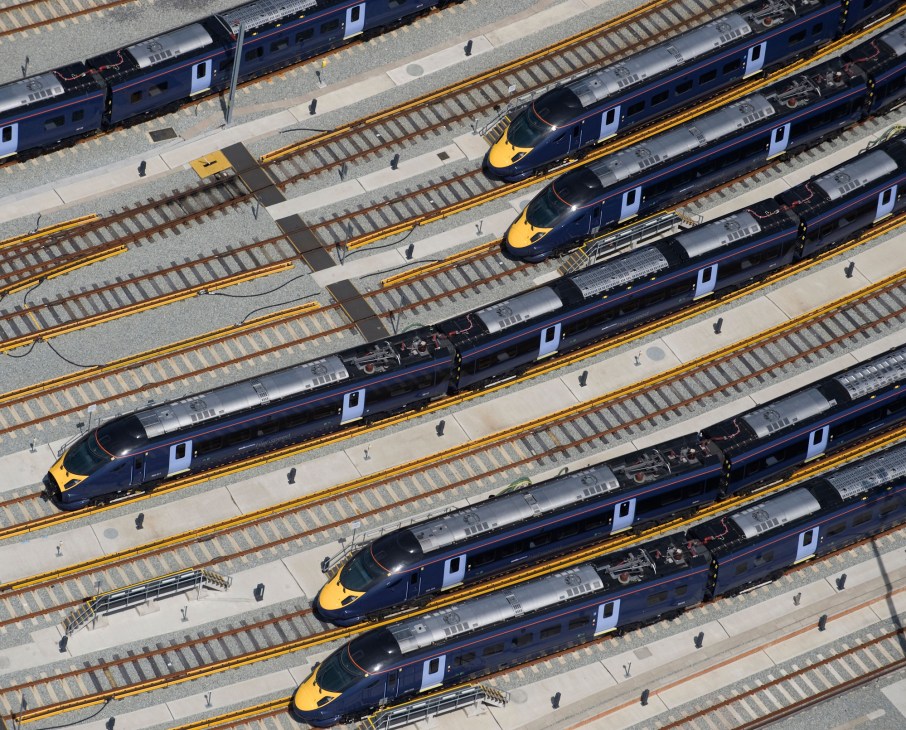 Multiple blue and yellow high-speed trains parked at rail depot with parallel tracks