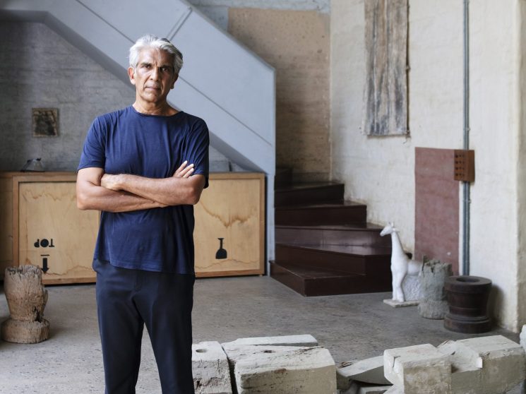 Bijoy Jain stands with arms crossed in his converted warehouse studio surrounded by stone blocks and materials