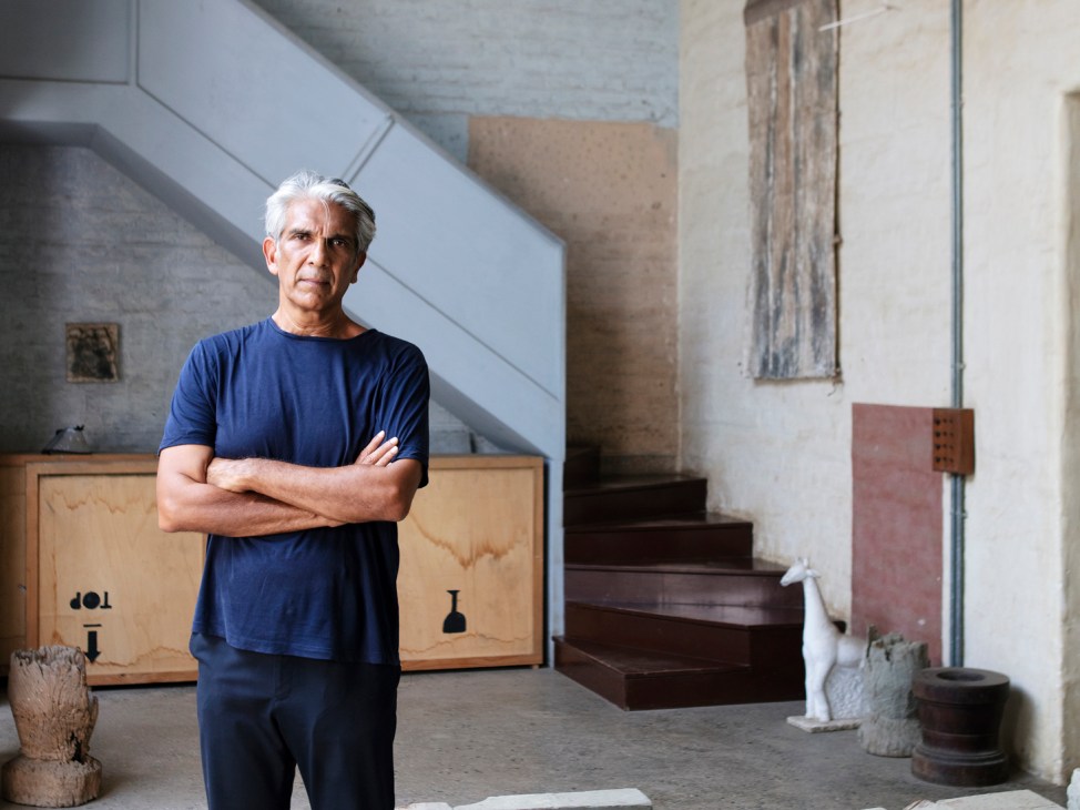 Bijoy Jain stands with arms crossed in his converted warehouse studio surrounded by stone blocks and materials