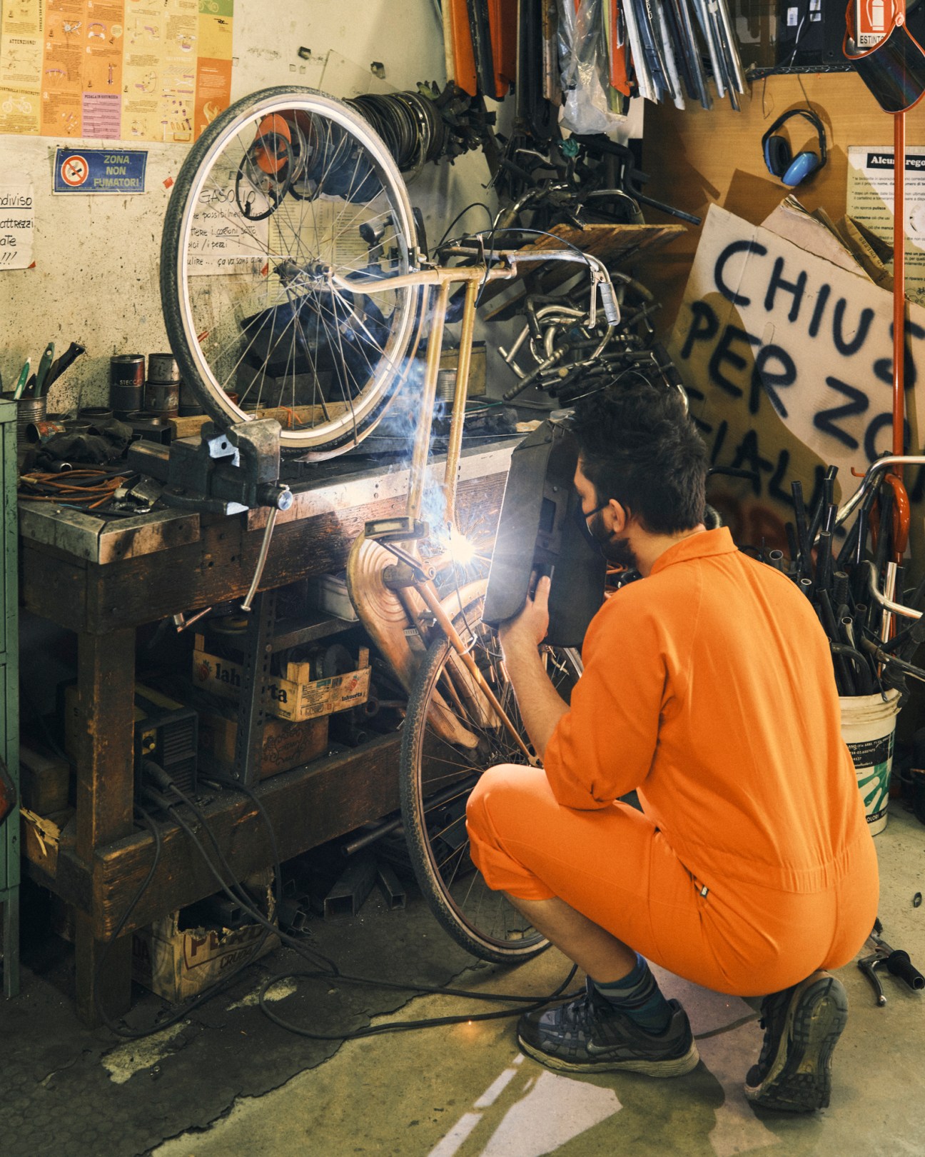Rocco Guarna in an orange boiler suit working with soldering equipment in the workshop