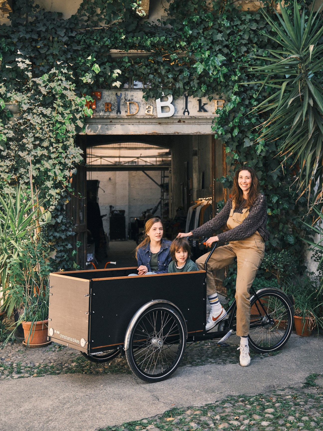 A woman with two children poses with a cargo bike outside Antonella Pesenti's Fridabike shop in Milan