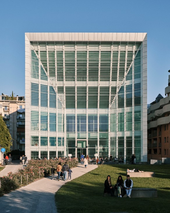 Modern glass and metal building facade with horizontal louvers in Bolzano, Italy.