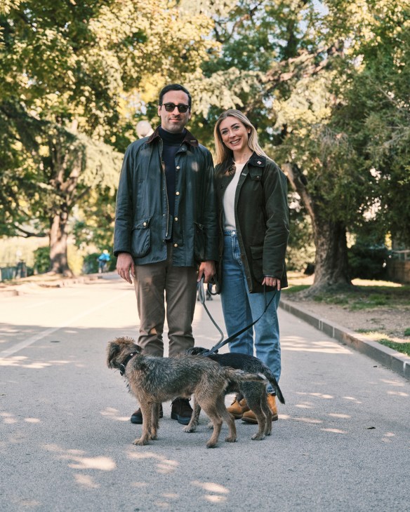 A couple walks with their dog on a tree-lined path in Bolzano, Italy.